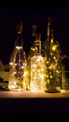 three bottles with lights in them sitting on a table