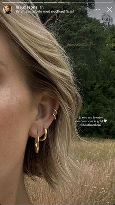 a close up of a person wearing earring's in front of a field