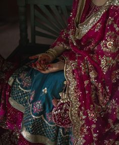 a woman in a red and gold dress sitting on a bench with her hands painted