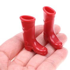 two red rubber boots sitting in the palm of someone's hand