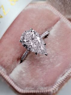 a diamond ring sitting on top of a pink velvet box