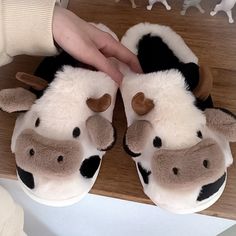 a pair of slippers with cows on them are being held by someone's hand