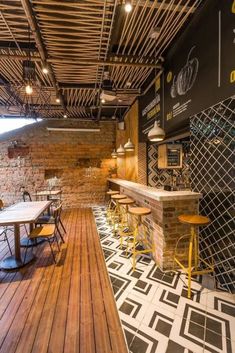 an outdoor restaurant with tables and stools next to a brick wall that has been painted black and white