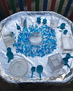 the table is set with blue and white decorations on aluminum foil, including plastic spoons