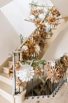 a staircase decorated with paper flowers and greenery for the holiday season is seen in this image