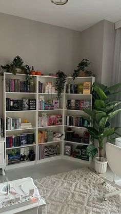 a living room filled with lots of white furniture and bookshelves next to a window