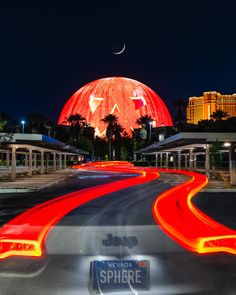 an image of a street at night with the moon in the sky and lights on