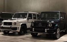 three mercedes benz g class suvs are parked in a showroom with other vehicles