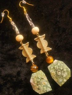 These exotic mixed media shoulder duster pierced earrings would be great for any woman of color, or when worn with a tan. Measuring 5" in length and nearly 1" in width, these are both comfortable and lightweight. The components include the following: faceted rhyolite jasper, tiger's eye, African lost brass wax components, beige bone rounds, and ornately carved bone tubes. The beads and stones are on sturdy, yet pliable metal wires which are suspended from a gold tone sterling silver (925) fish hook ear wire with a silicone back to prevent loss. OOAK Wearable Art from the Arlier of Kat Kouture. Will be smashing with olive, brown, orange, yellow, gold or any Autumn color. Unique Brass Earrings With Natural Stones, Unique Earrings With Natural Stones, Artisan Earrings With Natural Stones For Festivals, Unique Beaded Drop Earrings With Natural Stones, Exotic Dramatic, Glamorous Women, Art Statement, Jewellery Shop Design, Turquoise Western