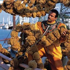 a man standing on top of a boat covered in lots of brown stuff next to the ocean