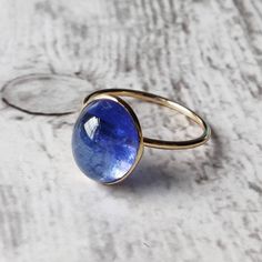 ITEM DESCRIPTION: >> The Ring is made from Solid 14K Yellow Gold. Gemstone used is absolutely natural and ethically sourced. >> Natural Tanzanite cabochon in oval shape is studded on it with utmost precision. >> This is a minimalist design which makes it a hassle free and everyday jewelry. Gem: Tanzanite Gem size: 9.5x12 mm and Oval Shape Gem weight: Gemstone option 1 : 3.96 carats Gemstone option 2 : 5.06 carats Gemstone option 3 : 3.35 carats Gemstone option 4 : 7.60 carats G Handmade 14k Gold Sapphire Ring, Modern Cabochon Sapphire Ring For Gift, Tanzanite Round Ring As A Gift, Tanzanite Round Rings As Gift, Round Tanzanite Rings For Gifts, Modern Sapphire Ring Gift, Modern Round Sapphire Ring As Gift, Modern Round Sapphire Ring Gift, Modern Tanzanite Round Rings