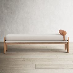 a wooden bench sitting on top of a hard wood floor next to a white wall