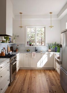 a kitchen with white cabinets and wood floors