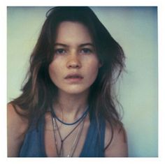 a woman with long hair wearing a blue tank top and necklaces on her neck