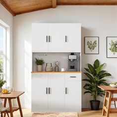 a kitchen with white cupboards and wooden table in the center, surrounded by potted plants