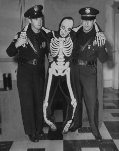 three police officers standing next to each other with a skeleton on their chest and arms