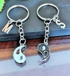 two metal key chains with the letter s on them and one has a charm attached to it