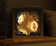 an illuminated paper cut scene with silhouettes of children in the woods