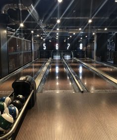 bowling balls are lined up on the pins in an empty bowling alley at night time