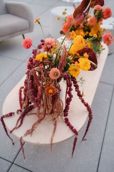 a wooden table topped with lots of different types of flowers on top of each other