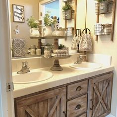 a bathroom with double sinks and wooden cabinetry in front of a mirror that has hanging planters on it