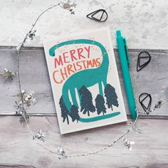 a christmas card sitting on top of a wooden table next to a pen and scissors