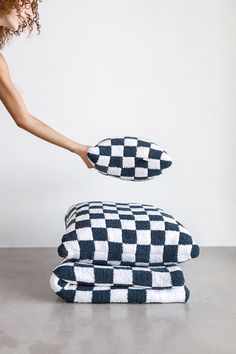 a woman reaching for two black and white checkered towels on top of each other