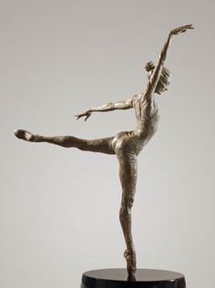 a statue of a woman doing a handstand on top of a wooden table