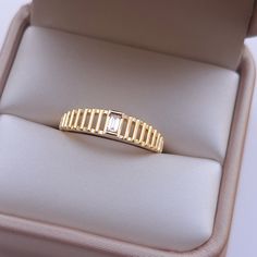 a yellow gold bracelet sitting on top of a cushion