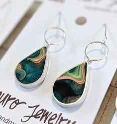 Discover the charm of our handmade teardrop earrings - a blend of skillfully shaped Sterling Silver wire and strip. What makes these pieces genuinely enchanting is the touch of eco-resin that brings out their unique colors. Take your pick from an array of captivating shades: classic Turquoise, deep Navy, bold Black, or warm Earth Tones. Size: Length: 1.75 inches Width: 0.5 inches Materials: Eco-resin, Sterling Silver Embrace timeless elegance with a modern twist. Our earrings not only elevate yo Handmade Artsy Teardrop Jewelry, Wire Wrapped Long Drop Teardrop Earrings As A Gift, Unique Hypoallergenic Teardrop Dangle Earrings, Unique Hypoallergenic Teardrop Earrings, Unique Teardrop Sterling Silver Earrings, Handmade Teardrop Drop Earrings As Gift, Handmade Teardrop Earrings For Gift, Unique Green Teardrop Earrings For Gift, Unique Teardrop Hypoallergenic Jewelry