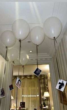 some white balloons hanging from the ceiling in front of a mirror with pictures on it