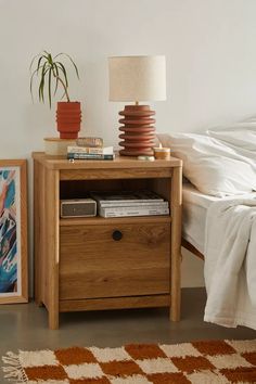 a nightstand with a lamp on it next to a bed