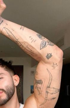 a man with tattoos on his arm and chest is holding his hand up in the air