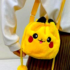 a person wearing a yellow pokemon backpack with a pom pom attached to it