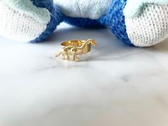 a small gold elephant ring sitting on top of a white table next to a stuffed animal