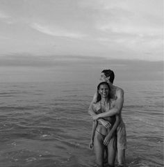 a man and woman are standing in the water together, one has his arm around the other's shoulder