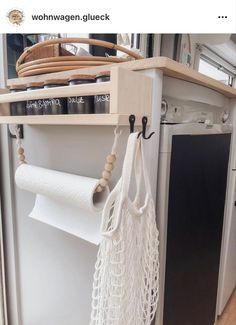 a kitchen with an open dishwasher next to a shelf that has some hanging items on it