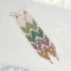 "Perfect calm greens and mauve paired with mixed gold! These beaded earrings are perfect for any occasion from brunch to birthdays, festivals to family gatherings.  These earrings are 4.25\" long and have gold-filled earwires." Botanical Beaded Earrings, Green Beaded Earrings, Beaded Fringe Earrings Pattern, Seed Bead Jewelry Patterns, Handmade Embroidery Designs, Beadwork Designs, Beaded Earrings Diy, Brick Stitch Earrings, Seed Bead Patterns