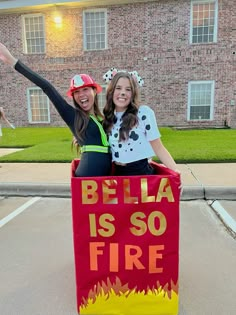 two girls are posing in front of a fire department sign that says, bella is so fire