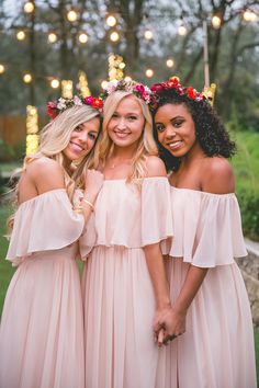 three bridesmaids in pink dresses posing for the camera with their arms around each other