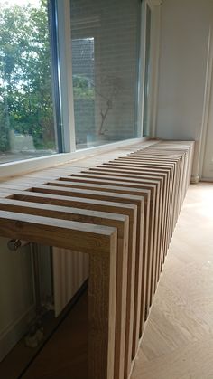 a wooden bench sitting in front of a window next to a hardwood floor and wall