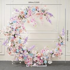 an arrangement of flowers arranged in the shape of a wreath on a wall with measurements