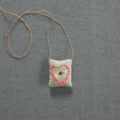 a small bag with a heart on it and a string hanging from the front, sitting on a gray surface