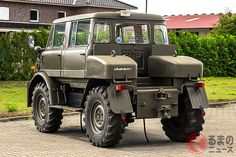 an army green truck parked in front of a house