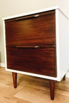 a white and wood dresser sitting on top of a hard wood floor next to a wall