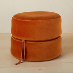 an orange round ottoman sitting on top of a wooden floor