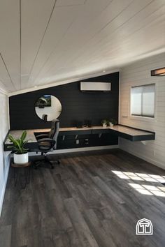 an office with black and white walls, wood floors and a desk in the corner