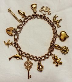 Vintage 9ct Gold Charm Bracelet Description: Elevate your jewellery collection with this exquisite vintage 9ct gold charm bracelet. Each charm is meticulously crafted, telling its own unique story and adding a touch of whimsy and elegance to your wrist. This bracelet is not only a piece of jewellery but a piece of history. Features:     Material: 9ct Yellow Gold     Charms Include:         Dolphin         Flying Bird         Ornate "18" Key         Vase/Jug/Pitcher         Teddy Bear         Hea Luxury Vintage Charm Yellow Gold Jewelry, Luxury Elegant Bracelets With Vintage Charm, Cheap Vintage Gold Charm Bracelet, Luxury Gold Antique-style Charm Bracelet, Vintage Gold Charm Bracelet With Dangling Charms, Vintage Gold Bracelets With Charms, Yellow Gold Vintage Charm Metal Charms, Gold Vintage Bracelets With Charms, Vintage Gold Charm Bracelet Gift