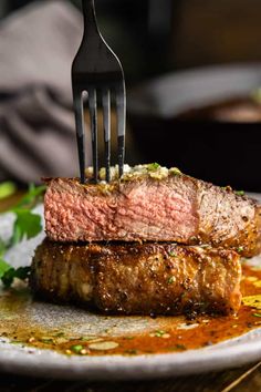 a piece of steak on a plate with a fork stuck in it