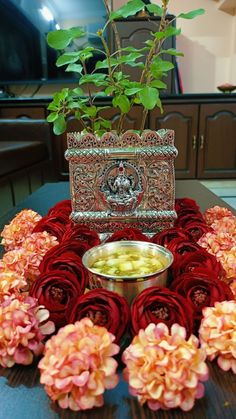 a flower arrangement on a table with candles and flowers in the center, surrounded by red roses